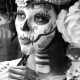 Fostoria News: Black-and-white portrait of a woman in sugar-skull face paint with a large rose in her hair.